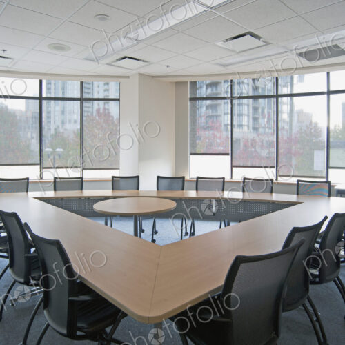 Large empty boardroom. A long narrow table in a triangle formation with a gap in the…