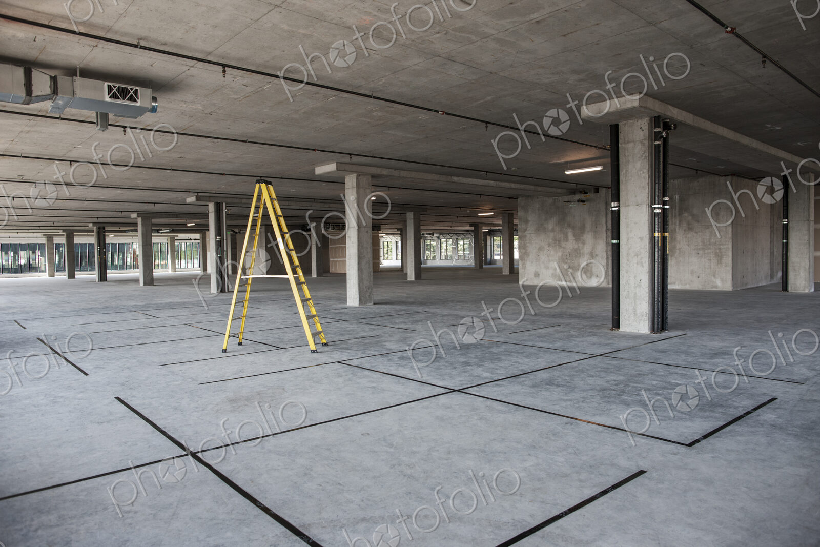 Large empty raw office space with a ladder set up on the floor.