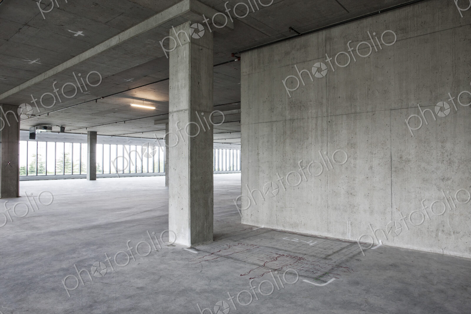 Large empty raw office space with plans sketched onto the floor in chalk.