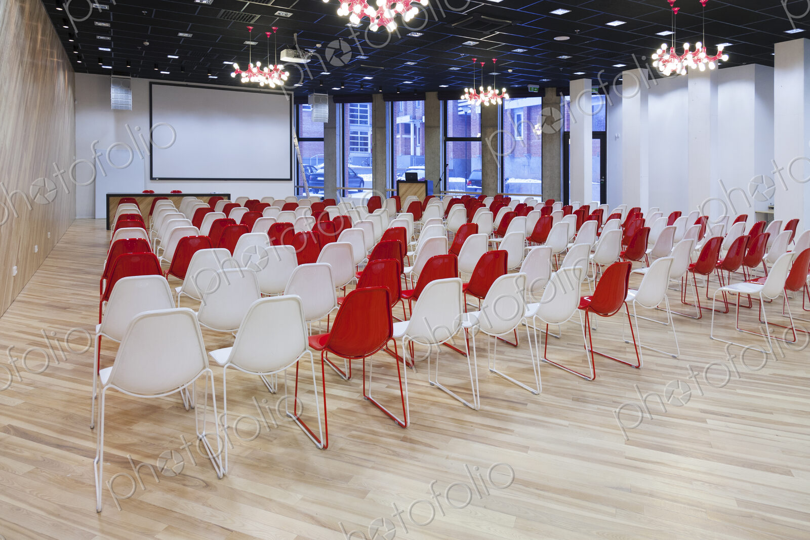 Large empty room with red and white chairs in rows, ready for a presentation