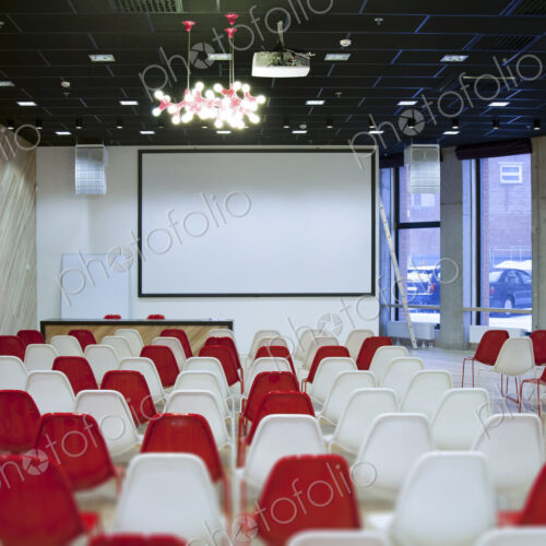 Large empty room with red and white chairs in rows, ready for a presentation