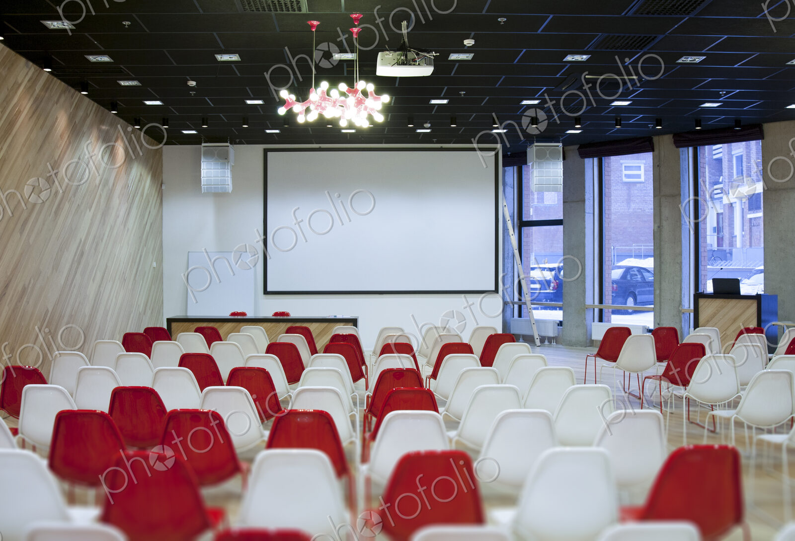 Large empty room with red and white chairs in rows, ready for a presentation