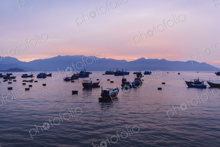 Large group of fisherman in traditional fishing boats on lake at sunrise, mountains in…