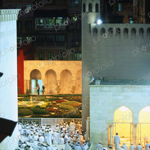 Large group of men gathered around mosque at dusk. Large group of men gathered around mosque at dusk.