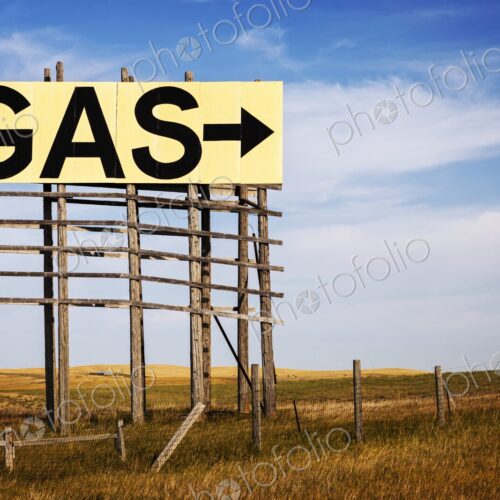Large roadside GAS arrow sign on a weathered wooden billboard stands in a rural… Large roadside GAS arrow sign on a weathered wooden billboard stands in a rural…