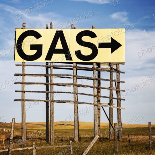 Large roadside GAS arrow sign on a weathered wooden billboard stands in a rural… Large roadside GAS arrow sign on a weathered wooden billboard stands in a rural…