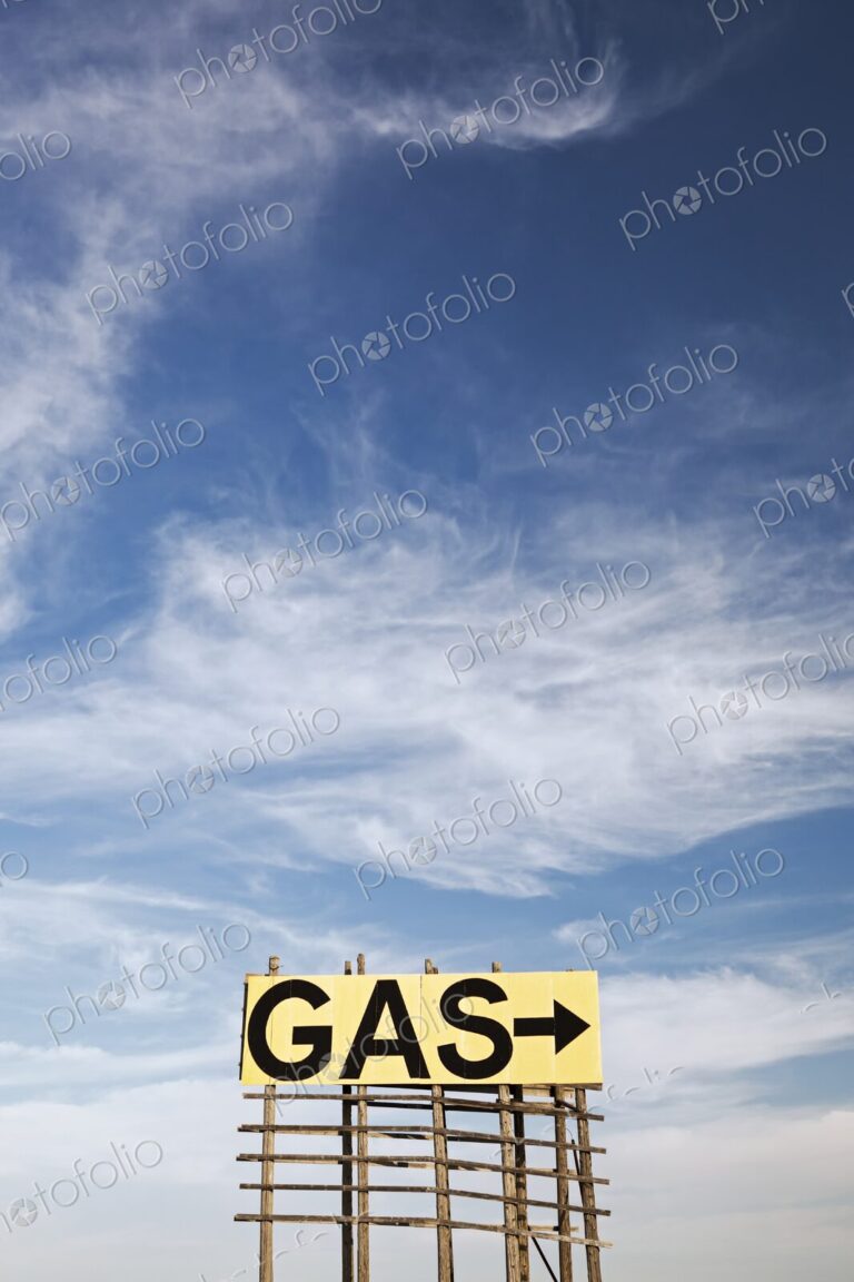 Large roadside GAS arrow sign on a weathered wooden billboard stands in a rural…