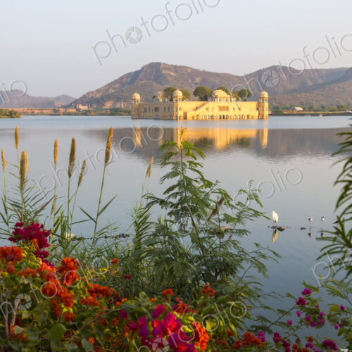 Large water palace in the middle of a lake, red flowers in the foreground. Large water palace in the middle of a lake, red flowers in the foreground.