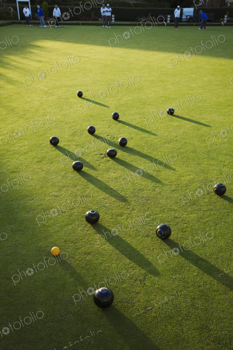 Lawn bowls balls positioned on a smooth playing surface, a bowls green. One small…