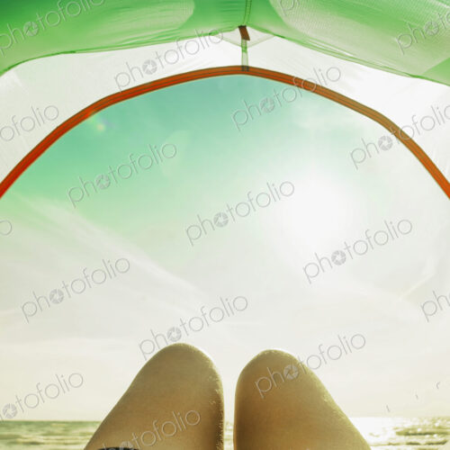 Legs in camping tent door on beach Legs in camping tent door on beach