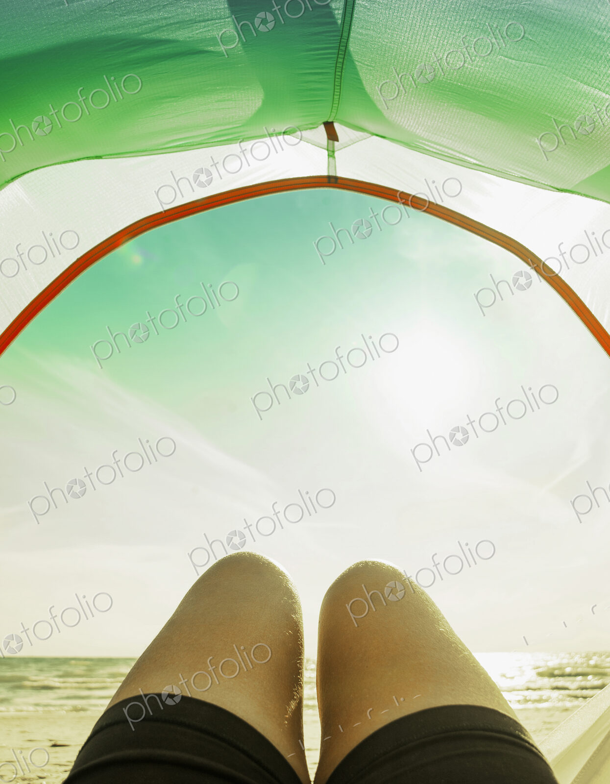 Legs in camping tent door on beach