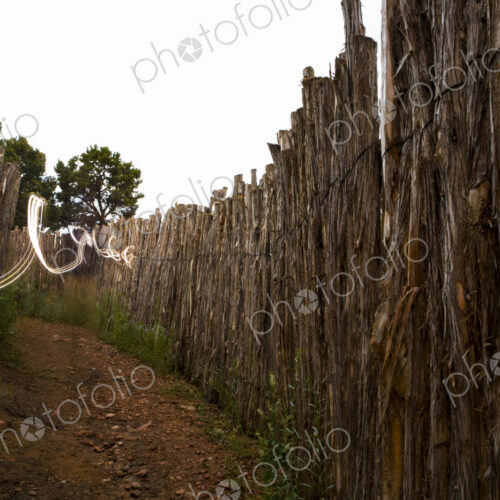 Light Painting, a trail of light winding along a fence by a narrow path.