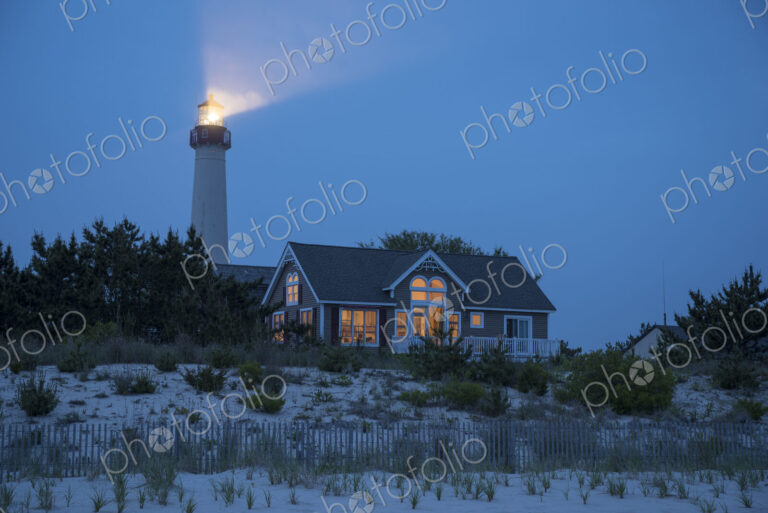 Lighthouse beaming near beach house
