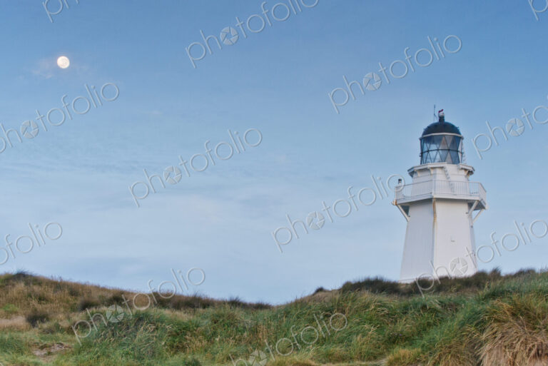 Lighthouse under moon in blue sky
