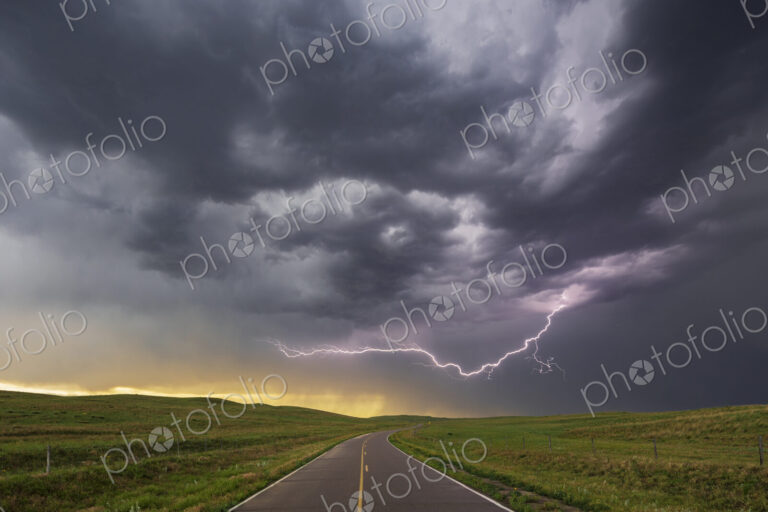 Lightning on the horizon at North Prairie Trace Road, black stormy sky over the land.