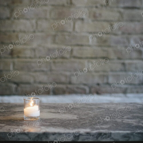 Lit candle on a marble bench at a city restaurant. Lit candle on a marble bench at a city restaurant.