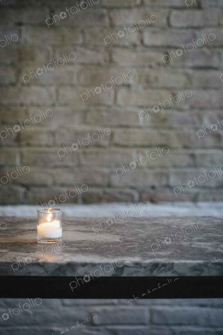 Lit candle on a marble bench at a city restaurant.