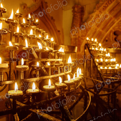 Lit candles in racks in a historic church