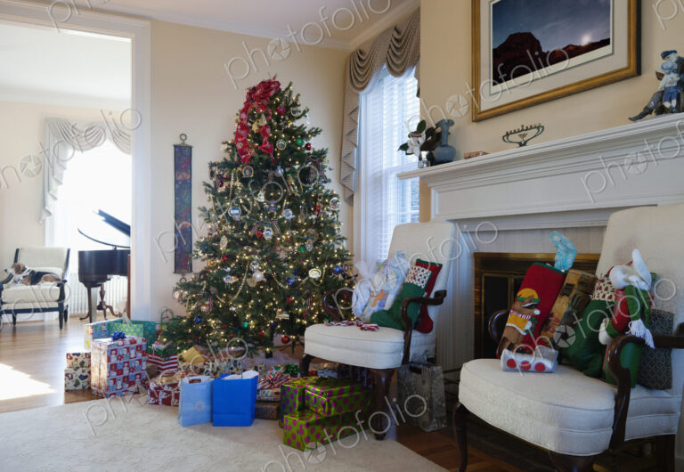Living room with Christmas tree and gifts, traditional decorations, fireplace and…
