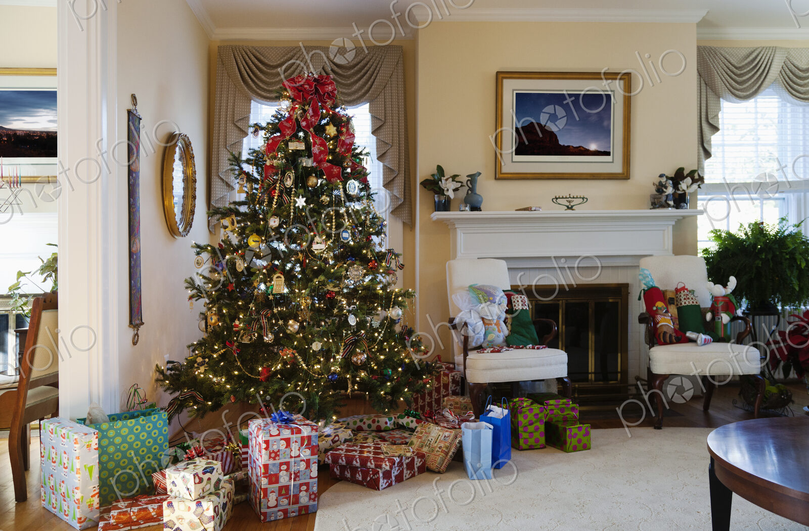 Living room with Christmas tree and gifts, traditional decorations, fireplace and…