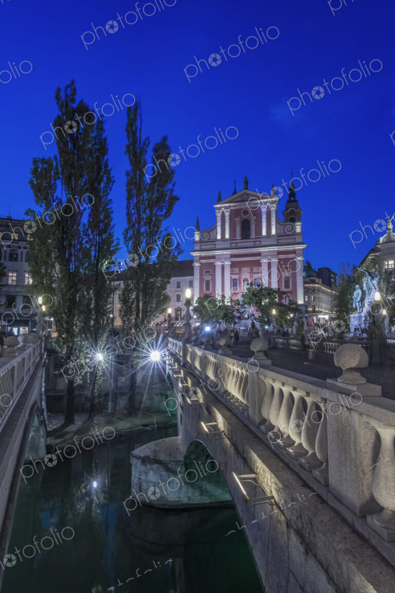 Ljubljana Castle at night, with the triple bridge in foreground.