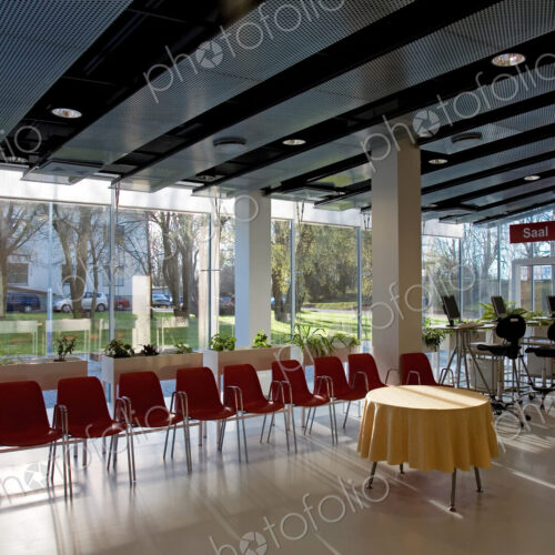 Lobby of hotel or conference centre with chairs and tables set up for event.