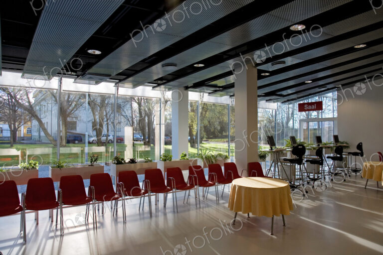 Lobby of hotel or conference centre with chairs and tables set up for event.