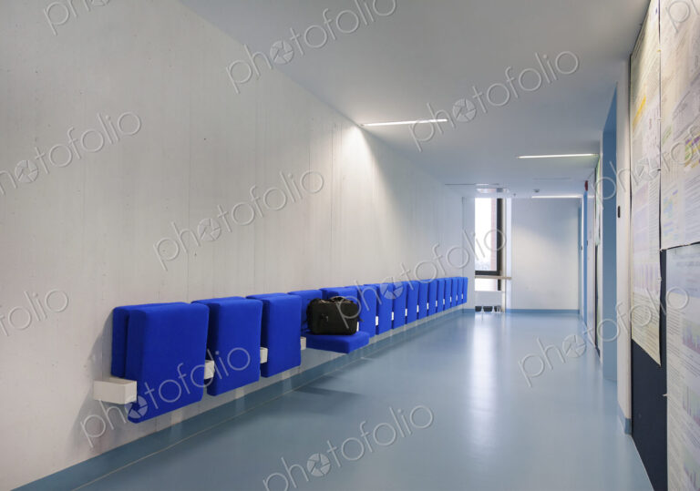 Long corridor in modern training college with blue flip up seats.