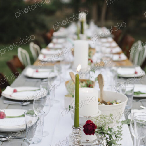 Long table set with plates and glasses, food and drink in a garden. Long table set with plates and glasses, food and drink in a garden.