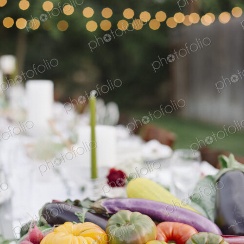 Long table set with plates and glasses, food and drink in a garden, a bowl of… Long table set with plates and glasses, food and drink in a garden, a bowl of…