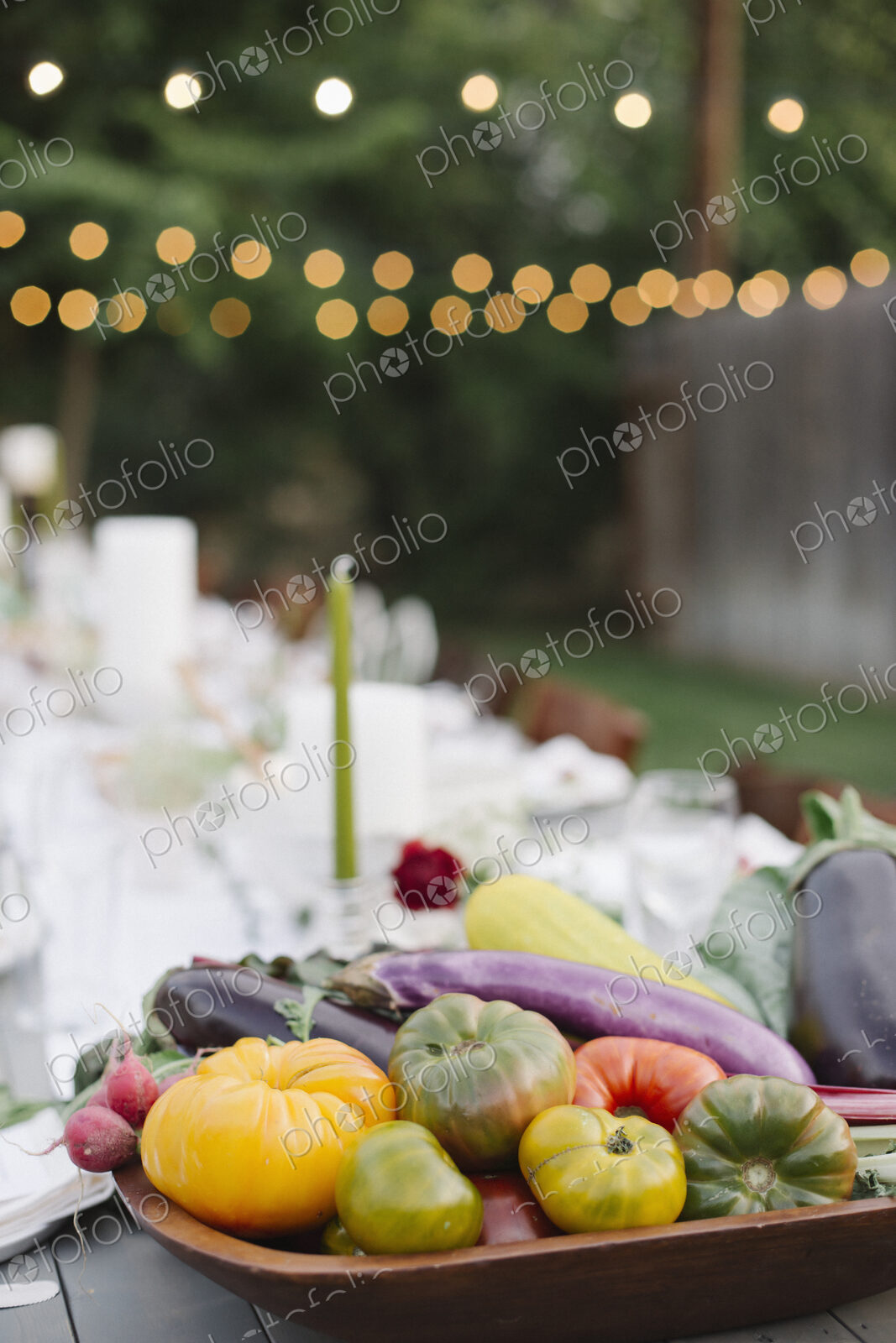 Long table set with plates and glasses, food and drink in a garden, a bowl of…