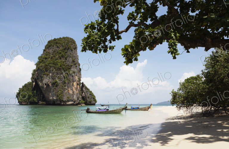 Long tail traditional boats beached and moored on Tham Phra Nang beach.
