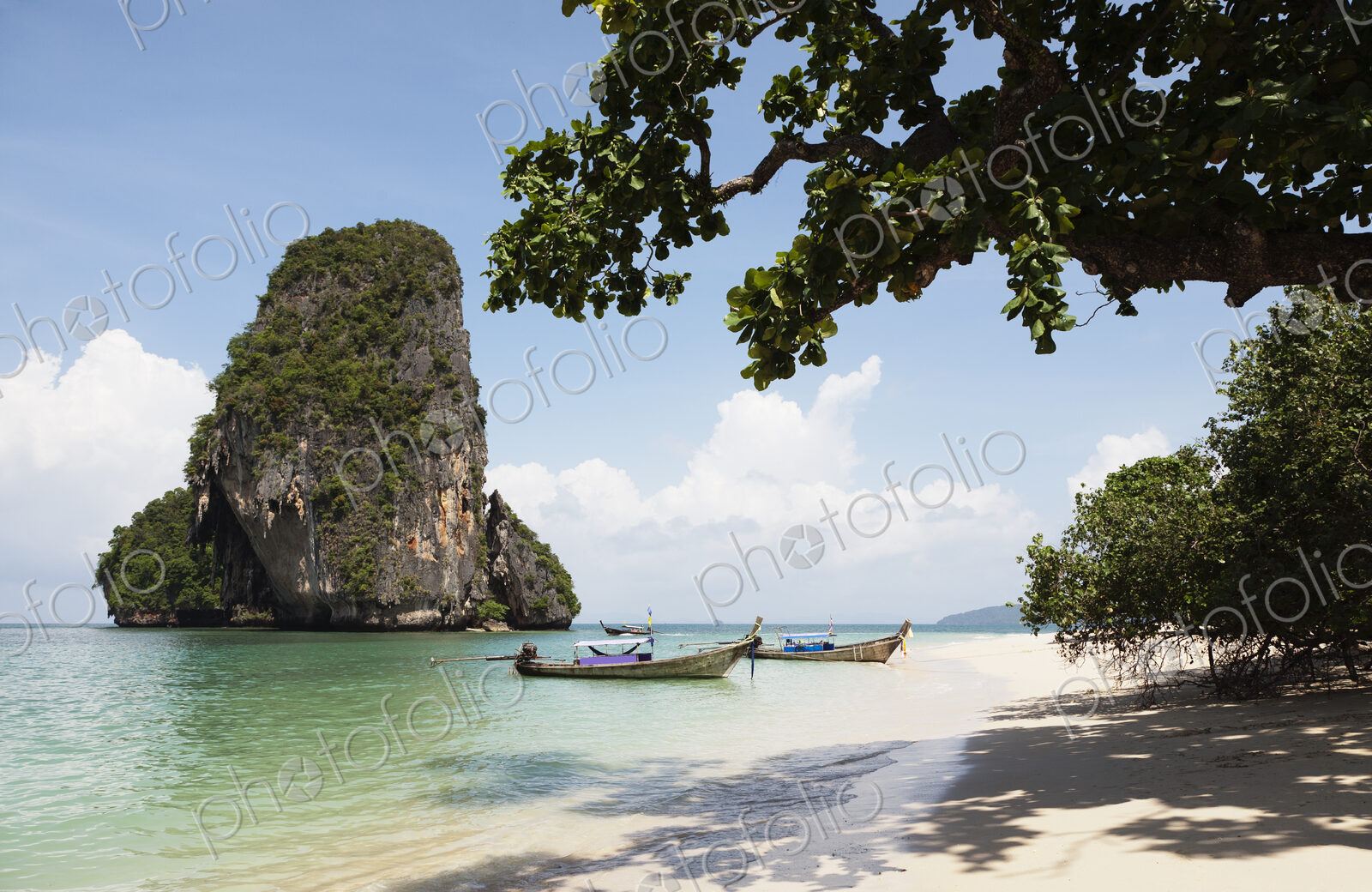 Long tail traditional boats beached and moored on Tham Phra Nang beach.