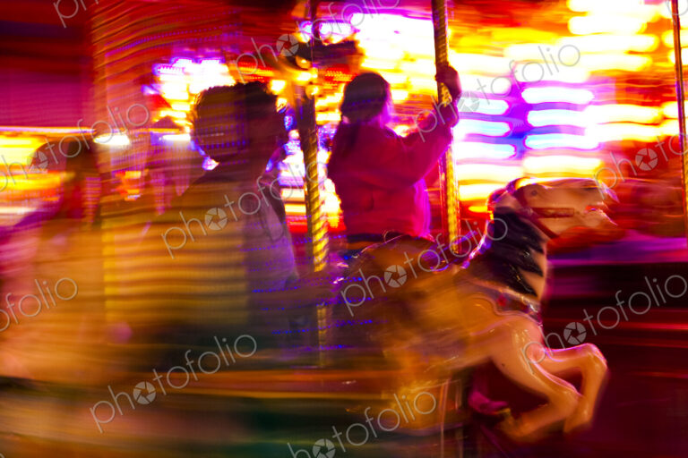Loof Carrousel at an amusement park in Spokane, blurred motion, people riding gallopers.