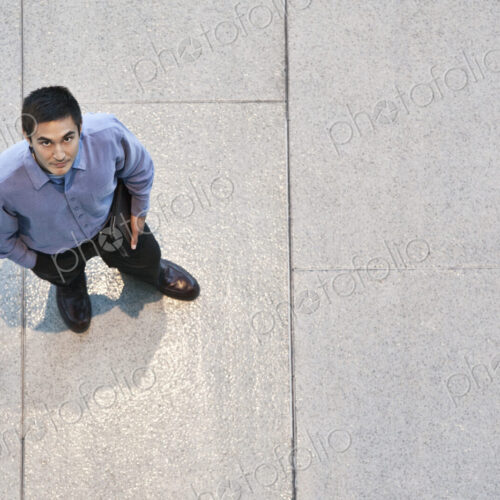 Looking down on a mixed race caucasian businessman standing in a business center lobby.