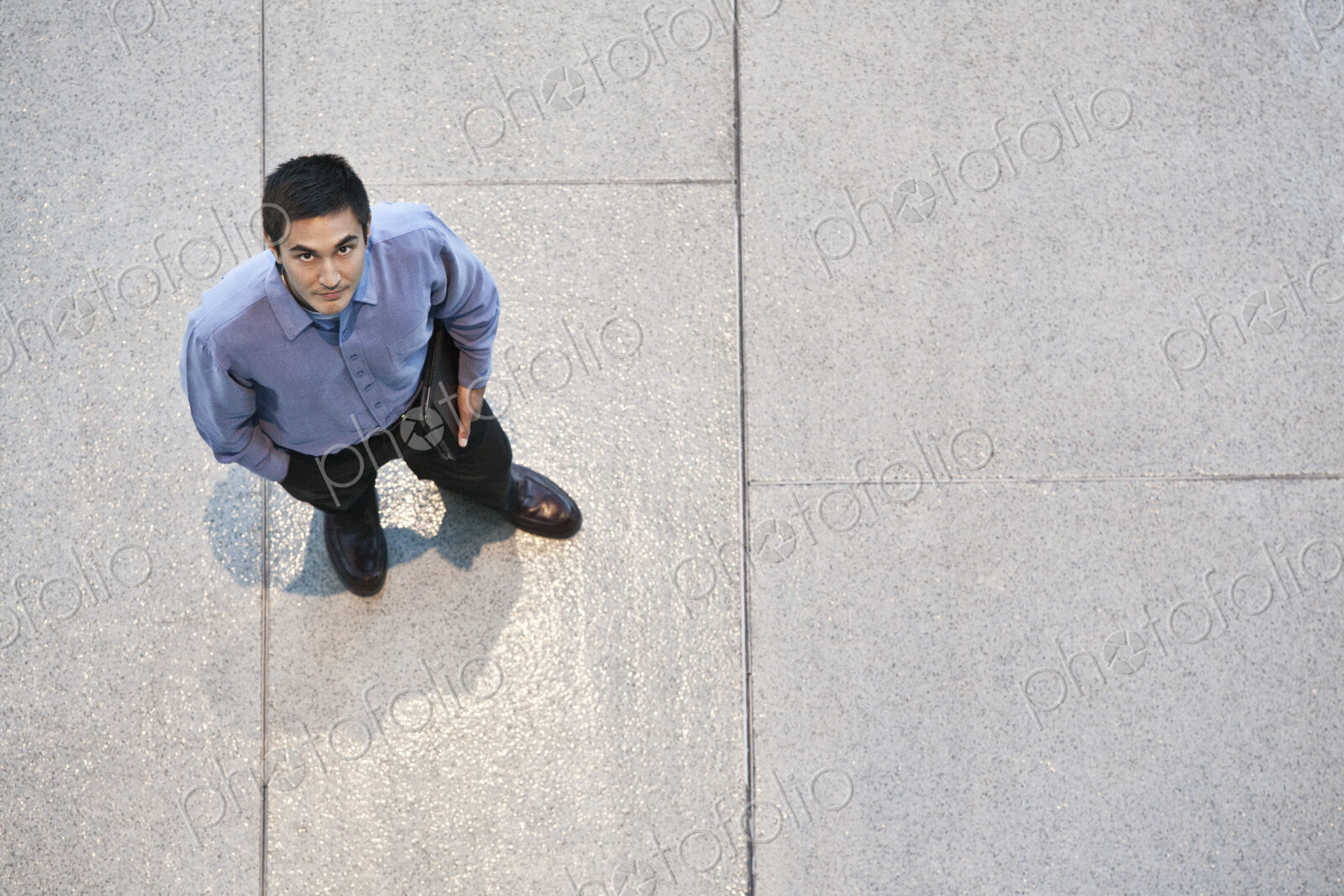 Looking down on a mixed race caucasian businessman standing in a business center lobby.