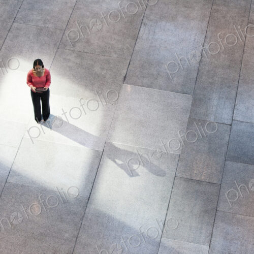 Looking down on a mixed race caucasian woman in a business center lobby.