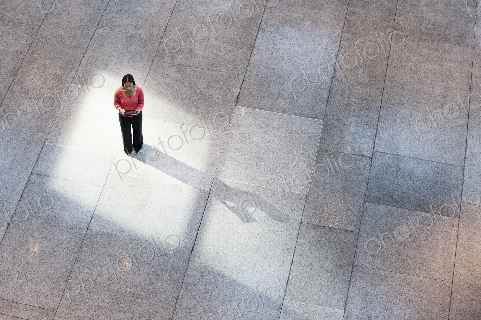 Looking down on a mixed race caucasian woman in a business center lobby.