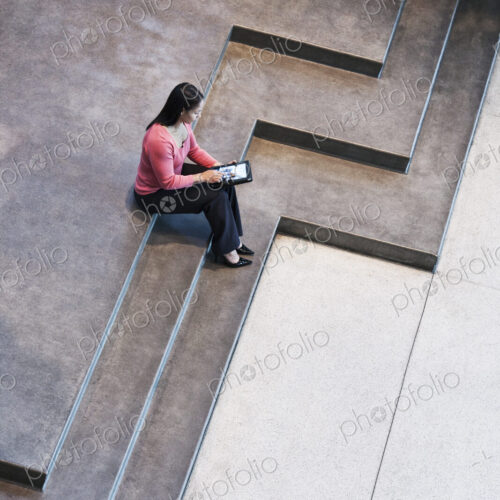 Looking down on a mixed race caucasian woman in a business center lobby.