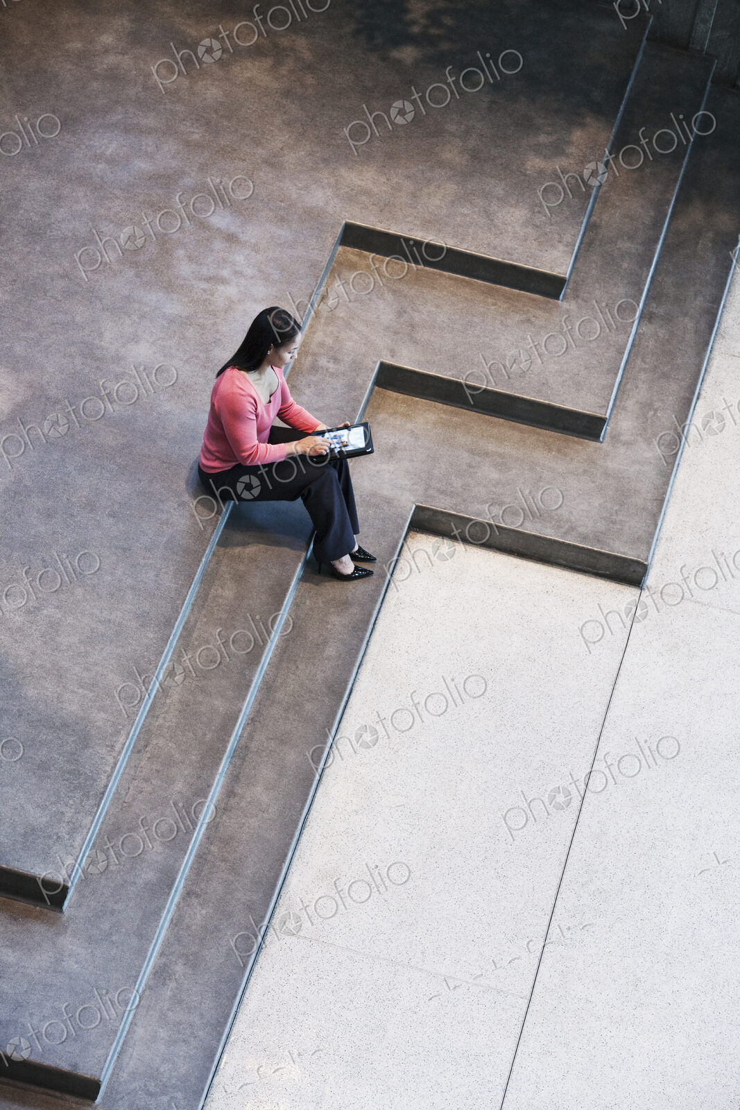 Looking down on a mixed race caucasian woman in a business center lobby.