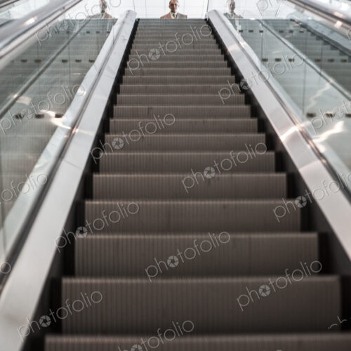 Looking up an escalator with a person about to get on the escalator in a convention… Looking up an escalator with a person about to get on the escalator in a convention…