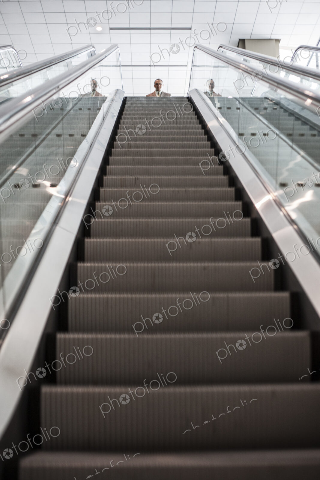 Looking up an escalator with a person about to get on the escalator in a convention…