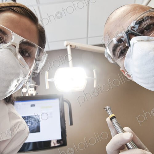 Looking up at a male dentist and a female technician from the viewpoint of a patient. Looking up at a male dentist and a female technician from the viewpoint of a patient.