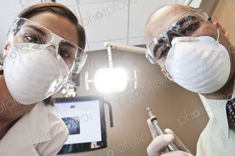 Looking up at a male dentist and a female technician from the viewpoint of a patient.