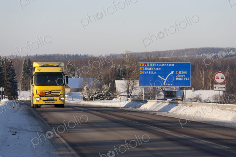 Lorry driving on snowy rural road woith road sign.