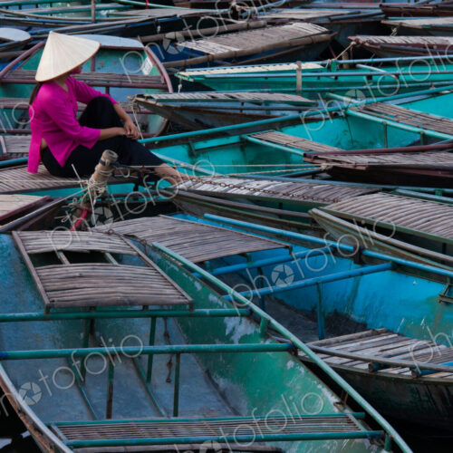 Lost in thought, a woman sits amidst a raft of boats. Ninh Binh, Vietnam Lost in thought, a woman sits amidst a raft of boats. Ninh Binh, Vietnam