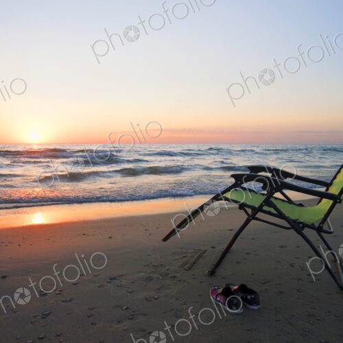 Lounge chair on beach at sunset