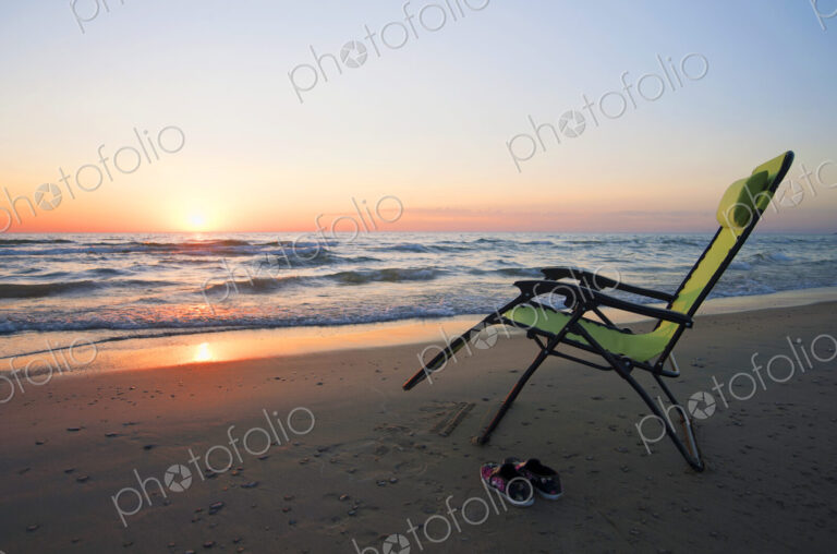 Lounge chair on beach at sunset