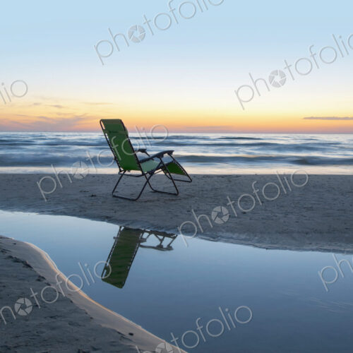 Lounge chair on beach at sunset