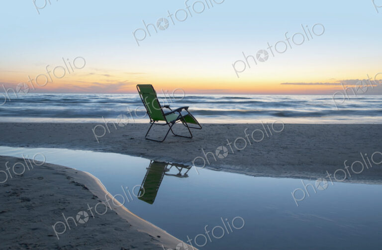 Lounge chair on beach at sunset